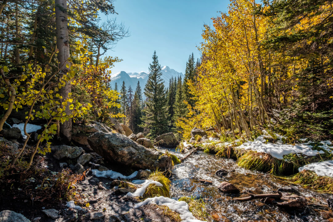 Rocky Mountain National Park with water, fall leaves, trees, mountains and first signs of snow